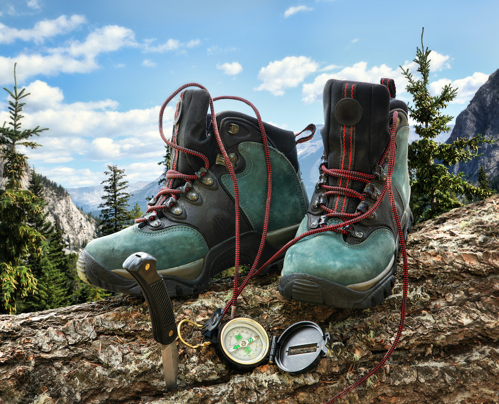 Pair of hiking boots with compass on fallen tree trunk