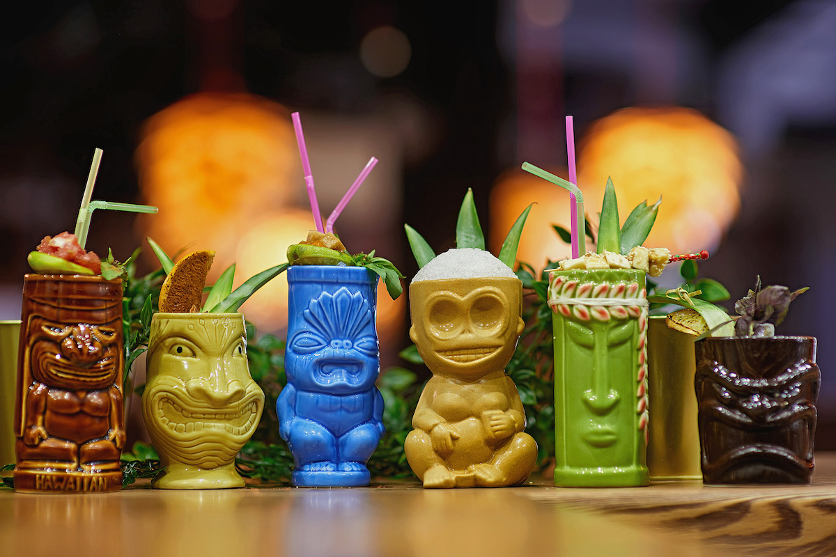 tiki mugs in a row on a bar